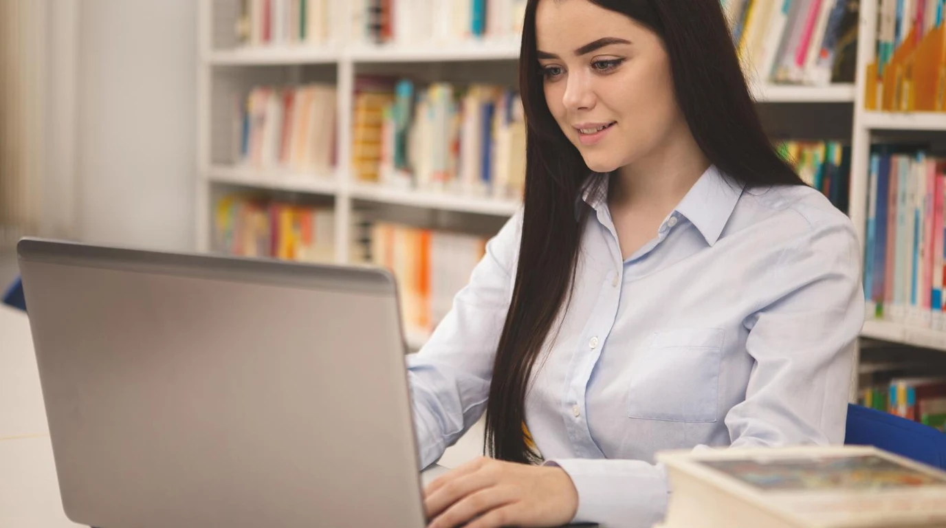 University Student Studying on Campus with Laptop and Books for RESP Planning